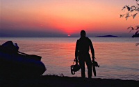Biologist SCUBA diver emerges from Lake Malawi at sunset